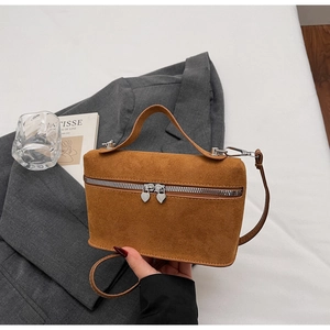 Detail of brown suede crossbody bag featuring a unique silver heart-shaped zipper puller