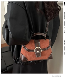 Detailed back view of a retro brown crossbody bag with large gold buckle on a model