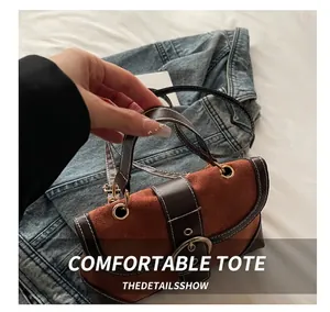 Detail of vintage brown suede stitching on handbag with gold metal hardware and top handle