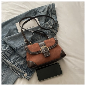 Close-up of vintage brown suede handbag with gold buckle and contrasting leather trim