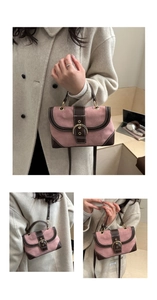 Detail of pink suede handbag featuring brown leather trim and golden belt buckle