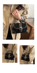 Macro shot of black matte leather shoulder bag with white contrast stitching and gold buckle