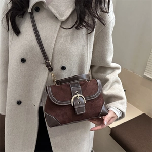 Vintage brown suede crossbody bag with gold buckle on a beige wool coat background