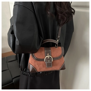 Detail of vintage brown suede and leather handbag with golden horseshoe buckle and strap