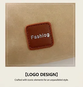 Detail of the brown leather logo patch and stitched beige suede texture on a crossbody bag