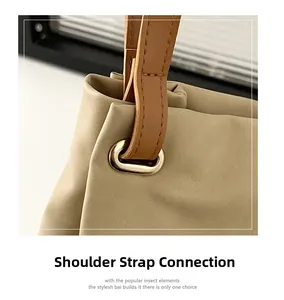 Close-up of beige tote bag shoulder strap with gold metal eyelet and detailed stitching