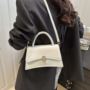 Structured white crossbody handbag with gold ring lock shown on a model in a black blazer