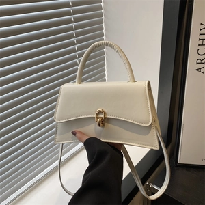 Elegant white structured handbag with a golden twist lock and curved base, held by hand