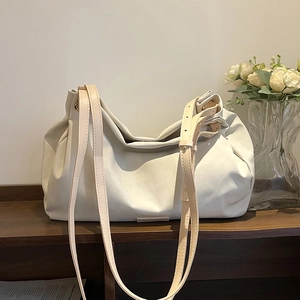 Chic ivory faux leather tote bag with brown adjustable straps on a wooden shelf