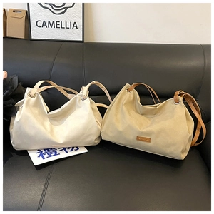 Detail of beige and khaki tote bags with brown leather handles on a dark sofa