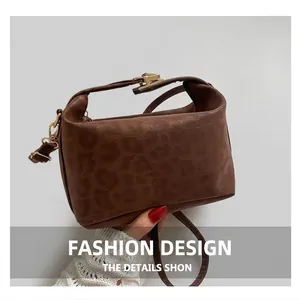 Detail of dark brown vintage shoulder bag with golden buckle and textured finish