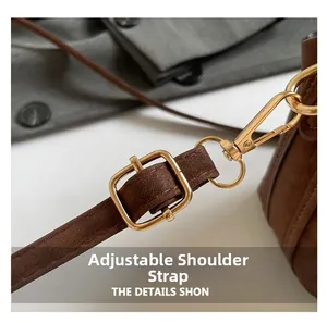 Detail view of adjustable dark brown suede shoulder strap with golden metal buckle hardware