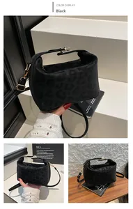 Close-up of black matte leopard print handbag featuring gold buckle and thin shoulder strap