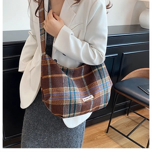 Detail of checkered wool dumpling bag featuring a power off label and wide shoulder strap