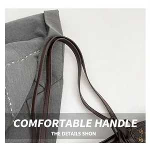 Close-up of the durable brown leather shoulder straps and gold logo texture on the tote bag