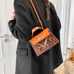 Orange leather leopard print handbag with gold lock shown as a crossbody on a model