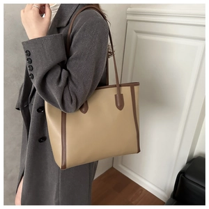 Model wearing a large two-tone beige and brown leather tote bag for office commuting