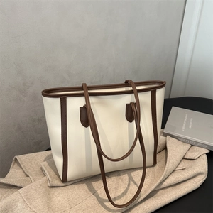 Detail of off-white tote bag with brown trim on beige coat for minimalist commute
