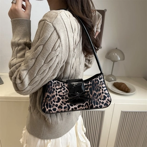 Leopard print underarm bag with black lacquer bow detail shown on a model