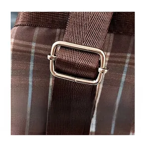 Close-up of adjustable nylon strap and silver buckle on a vintage plaid backpack