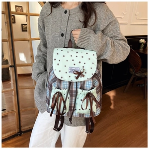 Detail of mint green bow and star print on a plaid school backpack for students