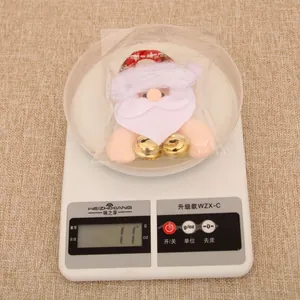 Detailed view of lightweight Santa plush ornament with bells on a digital scale