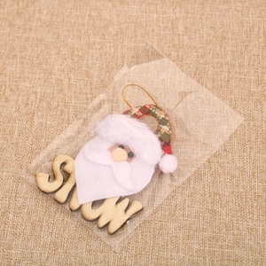 Detail of wooden SNOW letter sign with Santa doll pendant in plastic packaging