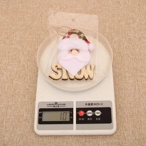 Detailed view of Santa Claus plush pendant with wooden SNOW letters on a digital scale
