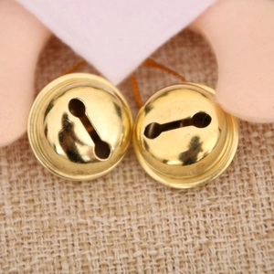 Macro shot of two golden metal bells with brown hanging loops for Christmas tree decoration