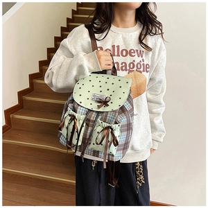 Détail d'un mini sac à dos à carreaux avec nœud et motifs d'étoiles sur escalier