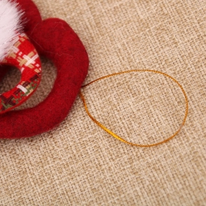 Macro shot of red felt Christmas tree ornament detail with plaid fabric and gold hanging rope