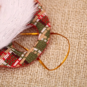 Détail d'ornement de Noël en fausse fourrure blanche, tissu à carreaux et cordon doré