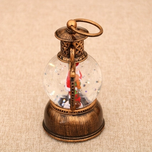 Detalle de farol navideño de bronce vintage con Papá Noel y purpurina brillante dentro