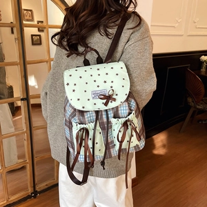 Sac à dos vintage vert clair avec motifs étoiles et carreaux marrons dans une pièce
