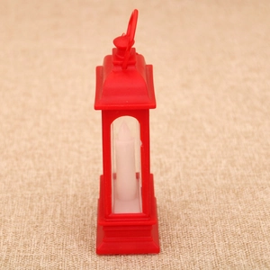 Close-up of a red vintage-style Christmas lantern with internal LED candle on burlap