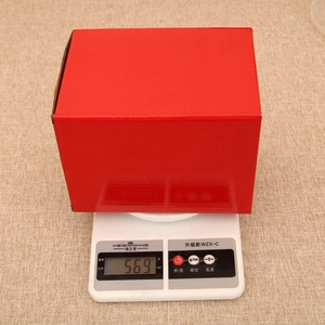 Casetta di Natale LED rotante di 569g in scatola rossa su bilancia digitale da cucina bianca