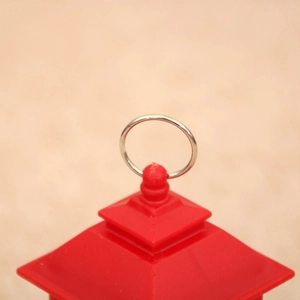 Detail showing the top silver hanging ring and red layered roof structure of a lantern