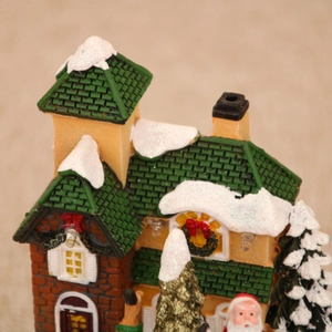 Dettaglio della casa di Natale dipinta a mano con tetto verde innevato e ghirlande