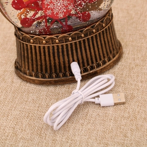 Detailed view of bronze vintage embossed base and USB cable of a Christmas snow globe lantern