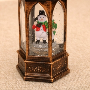 Close-up of vintage bronze snowman water lantern with swirling silver glitter inside
