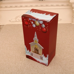 Close-up of red Christmas gift box featuring snow scenes and nativity church illustrations