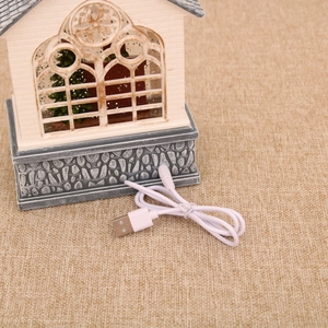 Detail showing the USB power cable and vintage brick wall base of the Christmas house lantern