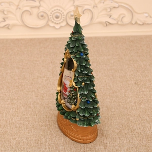 Detail of a lighted Christmas tree ornament with musical snow scene and gold scroll base