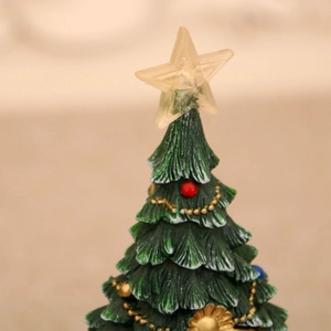 Close-up of a Christmas tree miniature with music, glowing lights, and snowy texture