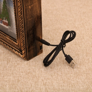 Detalle del cable de alimentación USB conectado a la caja de música navideña