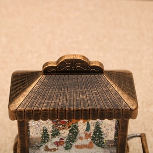 Close-up of vintage bronze Christmas snow globe lamp with intricate scrollwork and snow