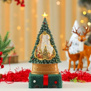 Close-up of a glowing musical Christmas tree snow globe with an ornate gold base