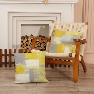 Geometric abstract cushion covers in yellow and grey on a Nordic woven chair in home setting