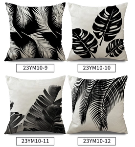 Detailed close-up of four linen pillow covers with black tropical leaf prints