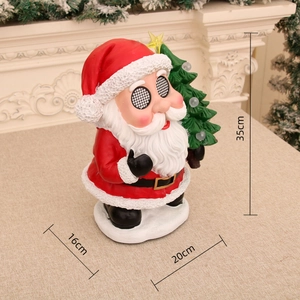 Close-up of Santa music box with a thumbs-up pose next to a decorated Christmas tree